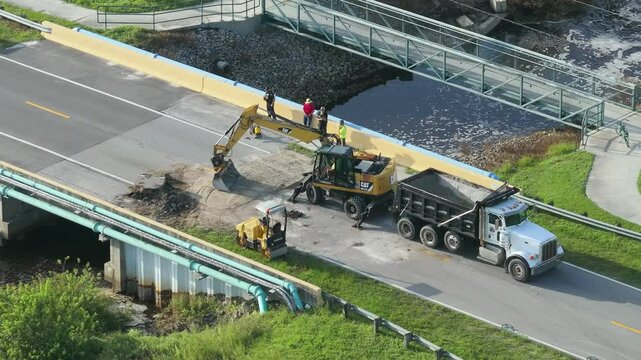 Reconstruction of damaged road bridge destroyed by river after flood water washed away asphalt. Rebuilding of ruined transportation infrastructure