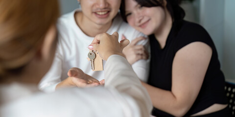 Obraz premium Happy Couple Receiving Keys to New Home from Real Estate Agent in Modern Apartment Setting