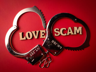 Metal handcuff with text LOVE SCAM on a red background