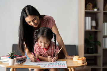 Mother and Daughter Engaged in Creative Learning Activity at Home with Art Supplies and Books