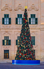 Decorated city Christmas tree with red and gold ornaments and glowing star topper