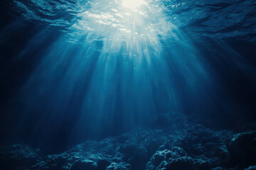 Obraz premium Underwater scene with sunlight rays illuminating the ocean floor.