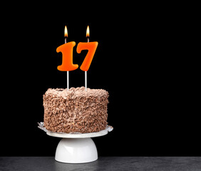 Birthday card with candle number 17 - Chocolate cake on black background.