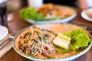 Papaya salad with rice vermicelli on a plate ready to eat on a wooden table in a restaurant