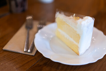 Coconut cake on a white plate on a wooden table in a bakery or coffee shop