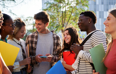 Multiracial student friends gathering after class, talking and having fun together outside...