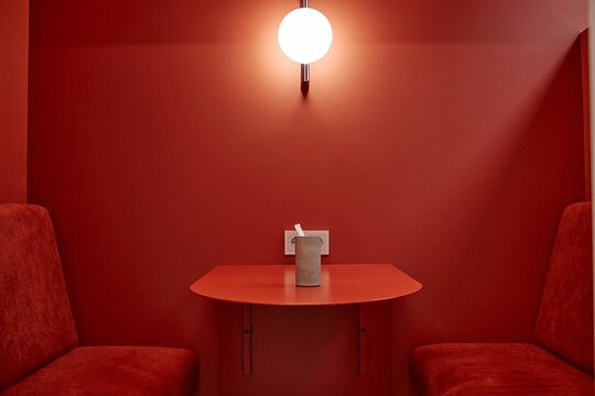 Fototapeta Background shot of table in vivid shade of red cafe booth featuring minimalistic design and lighting lamp on wall, copy space