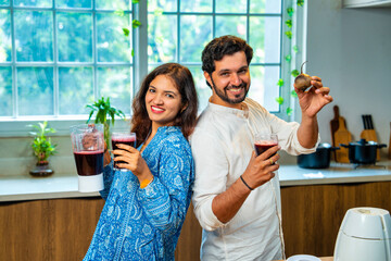 Indian wife serves fresh red beetroot juice to her husband in the kitchen, promoting healthy living