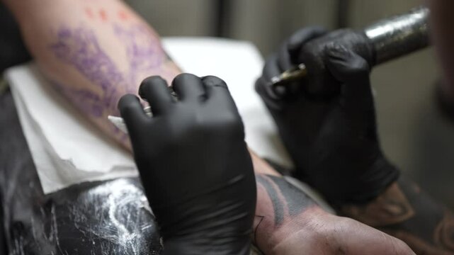 Plano detalle 4k de tatuador trabajando tatuando piel en un estudio de tatuaje