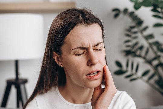 Close up of young woman suffering touching cheek, female feeling painful toothache. Teeth pain and dentistry, jaw pain, health care concept. Unhappy feel bad, diseases in oral, ache nerve and molar