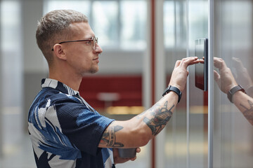 Side view of businessman entering access code on sensor touch screen for unlocking office room, modern security system concept, copy space