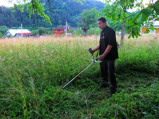 A man mows the grass at the country house in the village