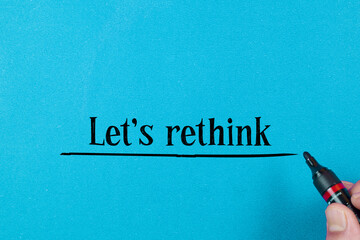 Concept words LET'S RETHINK written on blue background. Beautiful red table, red background. Businessman hand. Business concept. Copy space.