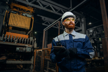 Portrait of male engineer wearing safety vest and working in manufacturing factory with bricks