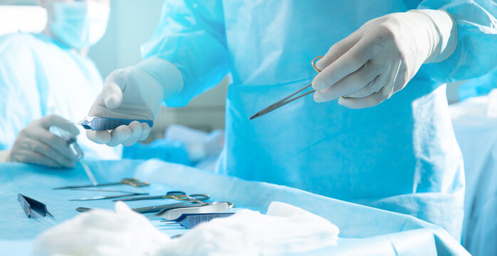 Professional surgery, blue light. Selective focus of surgical instrument with hand of surgeon during operation