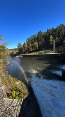 Rainbow on a river dam with falling water. Bobr River, Poland. © PRO Balance