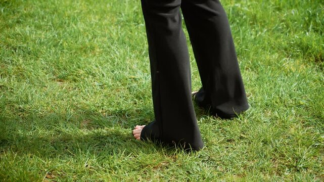Woman legs dancing rhythmically on grass to popular music. Female legs moving in sync on meadow, grooving to trendy beats. Lady feet tapping to lively rhythm on green field