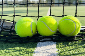  paddle tennis balls next to the net of a paddle tennis court