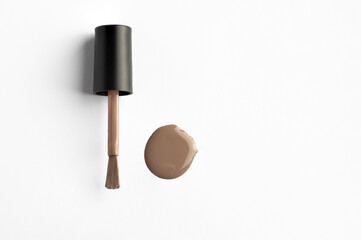 Top view of beige nail polish brush with nail smear at white background , catalogue style