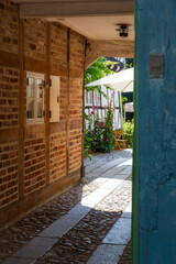 view to an courtyard garden through a narrow alley with a brick wall and window in Ribe, Denmark 