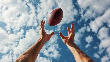 Hands catching football in mid-air, background of cloudy sky