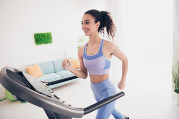 Energetic woman in stylish activewear enjoys treadmill workout in bright modern home interior