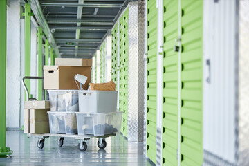 Background shot of dolly cart loaded with cardboard boxes storing personal belongings in hallway of...