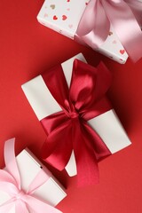 Gift boxes with bows on red background, flat lay