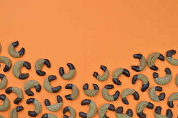 home made nougat crescents cookies with chocolate at the edge on orange background with copy space above