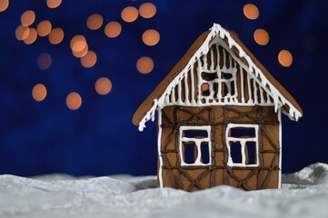 home made gingerbread house with bokeh sky out of blue velvet and christmas lights and copy space to the left