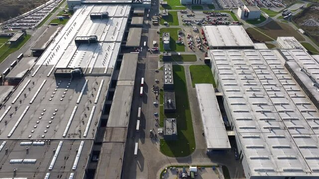 Truck manufacturing facility showcasing assembly process and logistics in a large production area during daylight hours