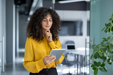 Businesswoman using digital tablet in modern office. Scene reflects confidence, focus, technology in professional setting, enhancing productivity and connectivity.