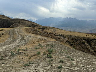 View of landcape with mountains and hills. The sun's rays in the sky shine beautifully through the clouds. Dirt road on a hill. Vivid natural scenery photo.