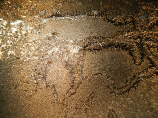 Natural hoarfrost on glass on frosty winter time - abstract background in shades of brown color. Topics: weather, texture, pattern, cold, climate, wallpaper