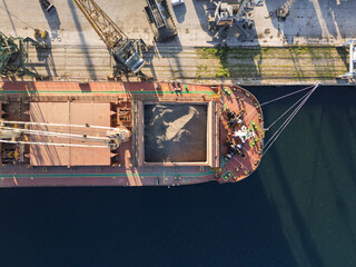 Close up top down view Loading ship with sunflower seed grain by cranes in port. Grain transportation by water. Export, import of dry cargoes around world