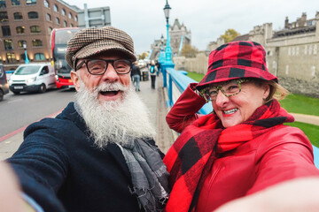 Happy senior couple taking selfie in london - Travel and joyful elderly lifestyle concept - Main focus on man face
