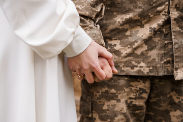 A Tender Moment: A Military Couple Holding Hands in Uniform and Wedding Attire