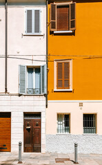 Sunlight illuminating the vibrant facade of a residential building in parma, italy, showcasing a mix of open and closed shutters, adding to the charm of the italian architecture
