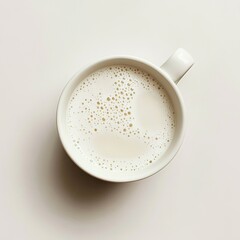 Cup of warm frothed milk on minimal white background.