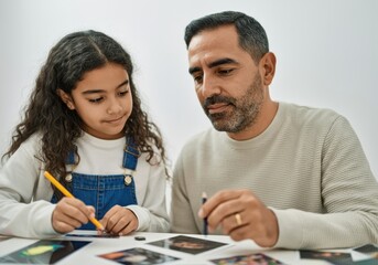 Fototapeta premium Father and daughter enjoying creative time together, drawing and coloring on printed photographs at home