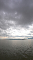 Dramatic sky over the lake with clouds and mountains in the background