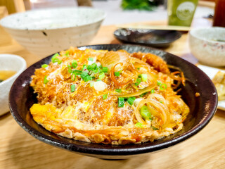 Japanese food concept. Chicken and egg rice bowl or Oyakodon in a black bowl with green onion topping.