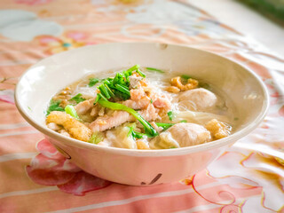 Thai street food. Thai noodle soup with meatballs and pork sliced and boiled green vegtables in a white bowl.