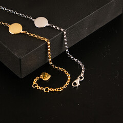 Jewelry for women. Gold and silver bracelets with a pendant on a black background. Black stand for...