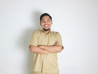 A young Asian man in brown khaki uniform showing confident gesture by folding her arms. Indonesian...