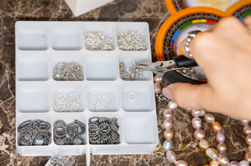 Close-up shot of small silver jewelry pieces lying in a white mesh box. DIY jewelry
