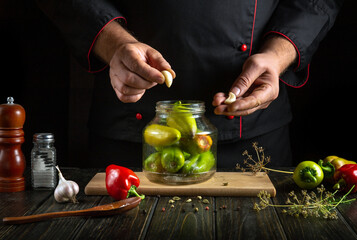 With a careful touch, garlic cloves are added to a jar of vibrant green and red peppers. A rustic...