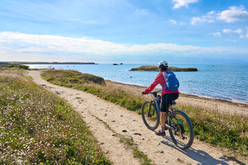 Fototapeta premium active senior woman cycling with her electric mountain bike at the wild coast of Quiberon peninsula, Brittany, France