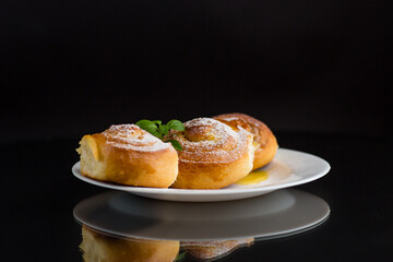 Baked goods. Sweet buns with cottage cheese filling and honey in a plate isolated on a black background