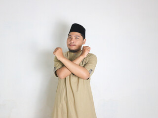 Asian Muslim man wearing a peci shows crossed arms, x sign gesture, gesturing warning or...